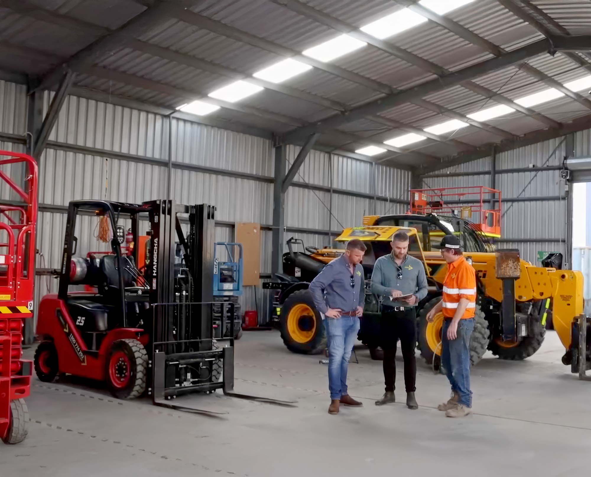 three men discussing servicing with a forklift to the left